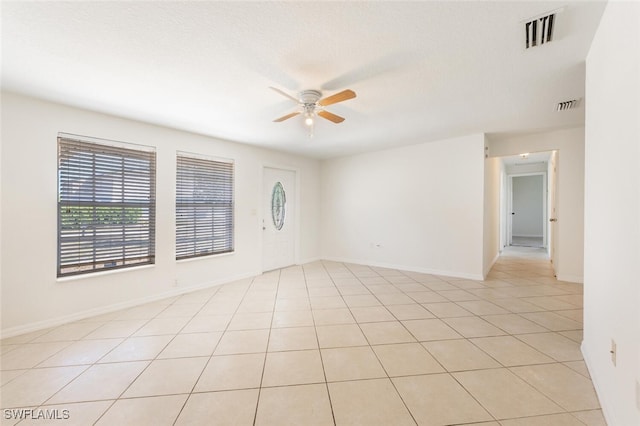 unfurnished room with ceiling fan, light tile patterned floors, and baseboards
