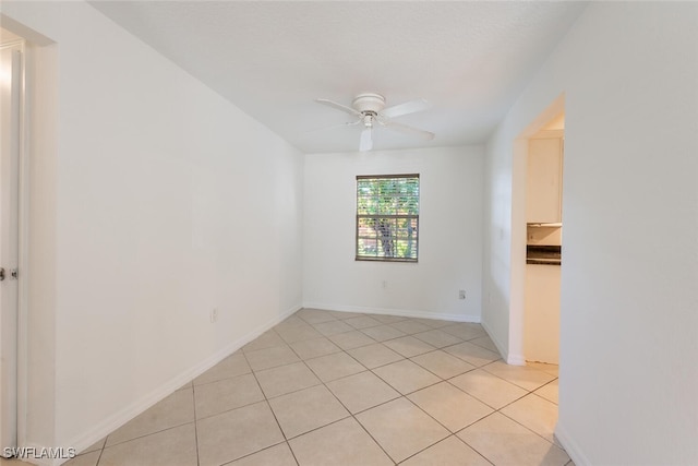 unfurnished room with ceiling fan, light tile patterned floors, and baseboards