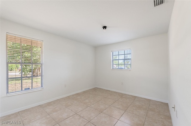 empty room featuring baseboards and light tile patterned floors