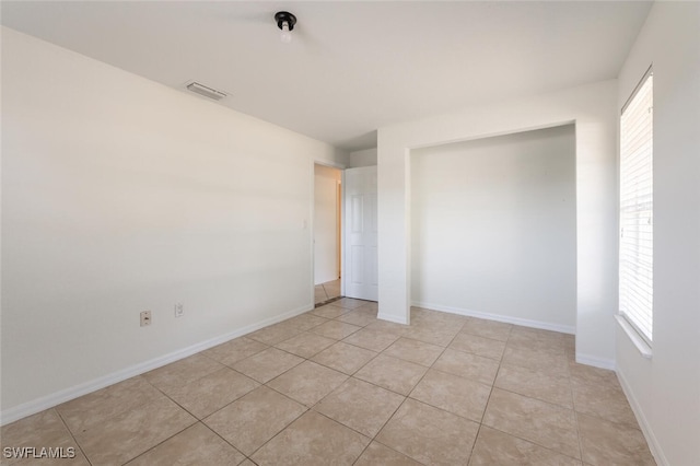 unfurnished bedroom with a closet, light tile patterned floors, and baseboards
