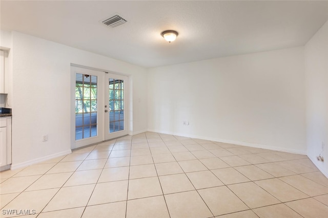 empty room with french doors, baseboards, and light tile patterned flooring