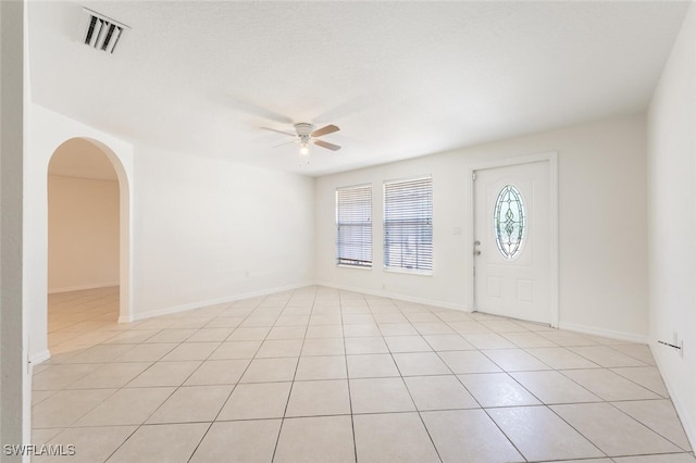 foyer entrance featuring ceiling fan, light tile patterned flooring, arched walkways, and baseboards