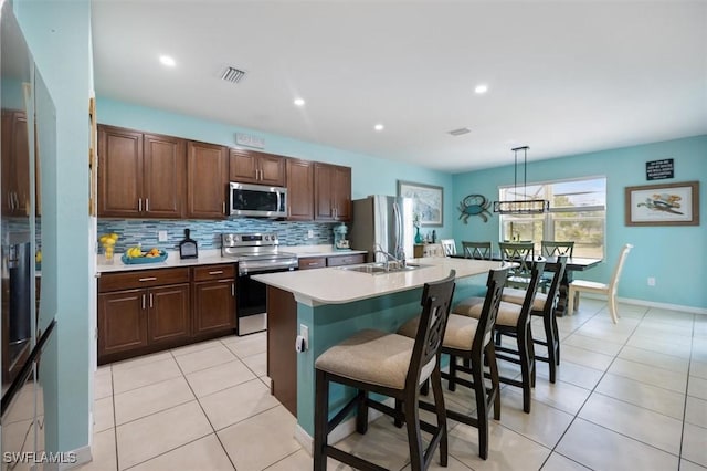 1713 NW 9th Ter, Cape Coral, FL 33993 - kitchen featuring stainless steel appliances, light countertops, decorative backsplash, a kitchen breakfast bar, and a center island with sink