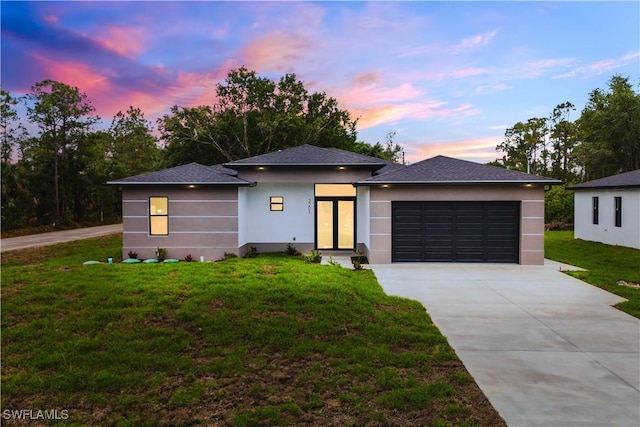 3201 18th St W, Lehigh Acres, FL 33971 - prairie-style house with concrete driveway, a yard, a garage, stucco siding, and french doors