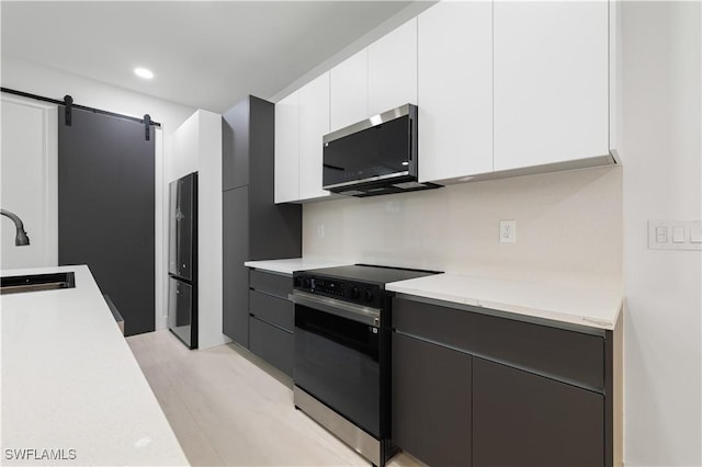 3201 18th St W, Lehigh Acres, FL 33971 - kitchen featuring black / electric stove, stainless steel microwave, a sink, white cabinetry, and modern cabinets