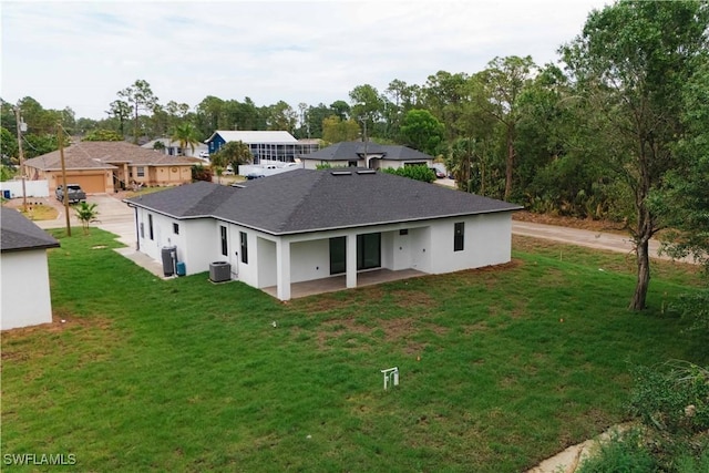 3201 18th St W, Lehigh Acres, FL 33971 - rear view of property with central AC, a patio, roof with shingles, a lawn, and stucco siding
