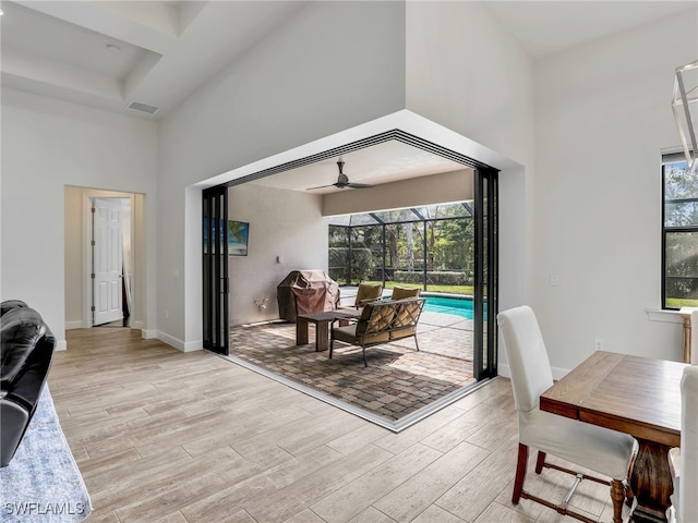 16289 Camden Lakes Cir, Naples, FL 34110 - living area featuring a towering ceiling, plenty of natural light, a ceiling fan, light wood-style flooring, and a sunroom