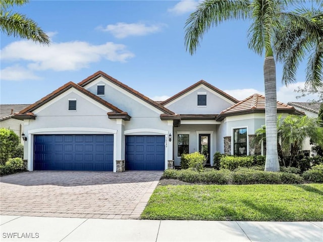 16289 Camden Lakes Cir, Naples, FL 34110 - view of front of property with stucco siding, decorative driveway, an attached garage, and stone siding