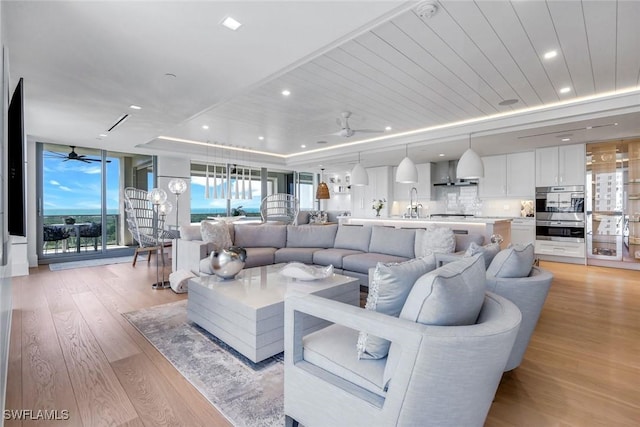 6897 Grenadier Blvd Unit 601, Naples, FL 34108 - living area with a raised ceiling, a ceiling fan, light wood-style floors, a wall of windows, and recessed lighting