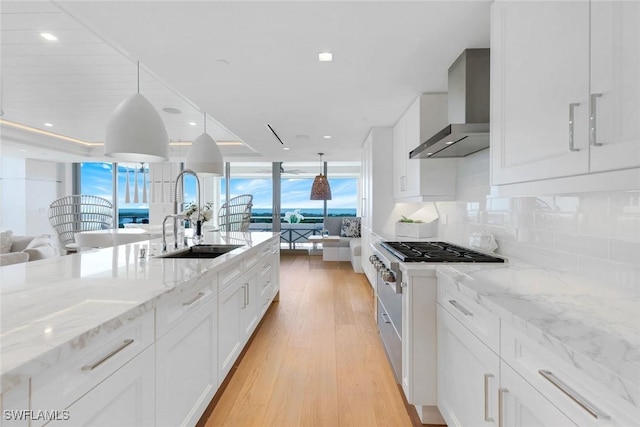 6897 Grenadier Blvd Unit 601, Naples, FL 34108 - kitchen featuring wall chimney range hood, a sink, open floor plan, decorative backsplash, and white cabinets