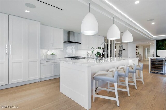 6897 Grenadier Blvd Unit 601, Naples, FL 34108 - kitchen with wall chimney range hood, beverage cooler, a sink, light wood finished floors, and recessed lighting