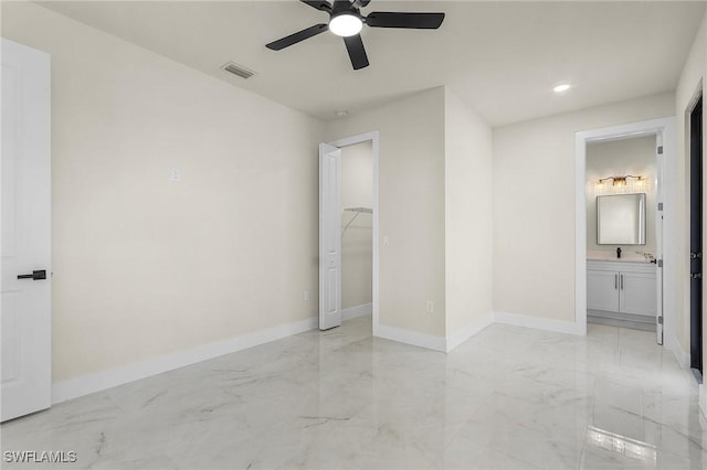 956 Columbus Blvd S, Lehigh Acres, FL 33974 - unfurnished bedroom with light marble finish flooring, a walk in closet, a sink, baseboards, and ensuite bath