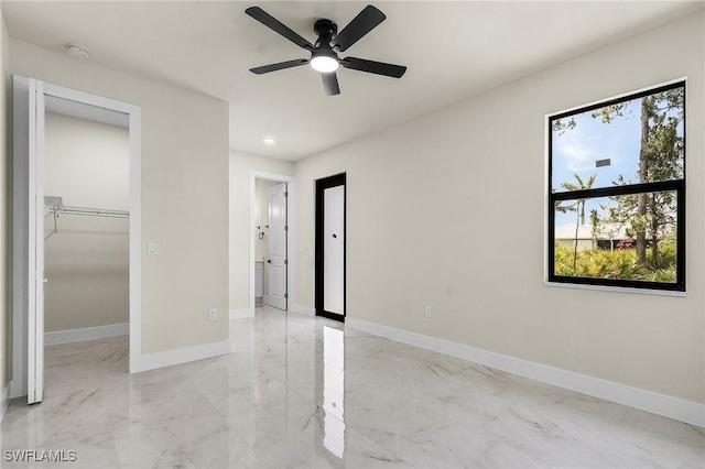 956 Columbus Blvd S, Lehigh Acres, FL 33974 - unfurnished bedroom featuring light marble finish flooring, baseboards, a spacious closet, ceiling fan, and a closet
