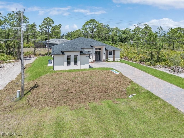 956 Columbus Blvd S, Lehigh Acres, FL 33974 - view of front facade featuring stucco siding, driveway, a front yard, and roof with shingles