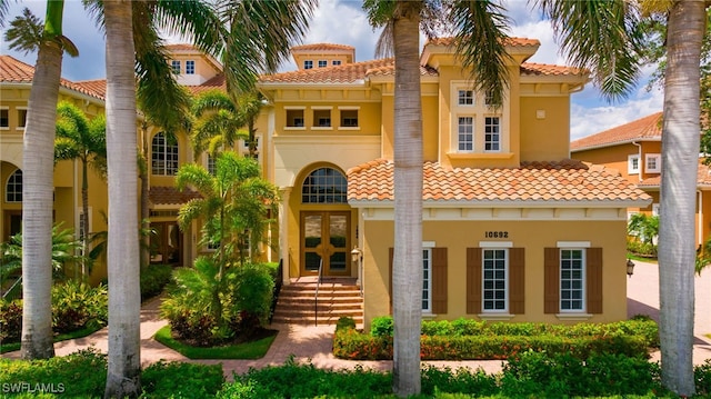 10692 Mirasol Dr Unit 1004, Miromar Lakes, FL 33913 - mediterranean / spanish-style home with french doors, a tile roof, and stucco siding