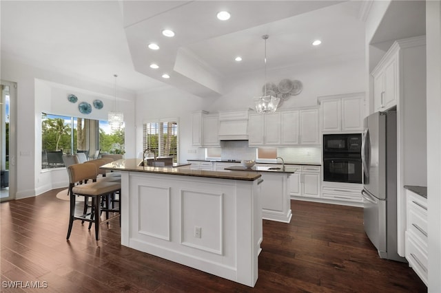 10692 Mirasol Dr Unit 1004, Miromar Lakes, FL 33913 - kitchen featuring black appliances, an island with sink, a chandelier, decorative backsplash, and white cabinetry