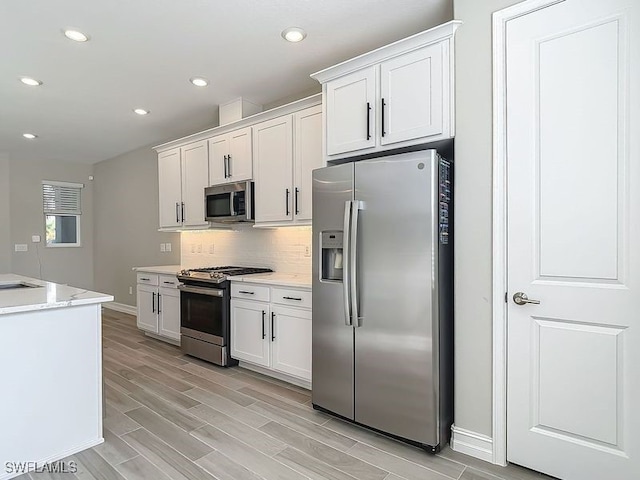 4564 Almada Ln, Wesley Chapel, FL 33543 - kitchen featuring appliances with stainless steel finishes, baseboards, white cabinetry, light wood-type flooring, and tasteful backsplash