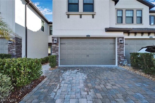 4564 Almada Ln, Wesley Chapel, FL 33543 - view of front of house with stucco siding, an attached garage, decorative driveway, and stone siding