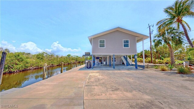 8161 Moyer Ln, Bokeelia, FL 33922 - rear view of property featuring a carport, stairway, driveway, a porch, and a water view