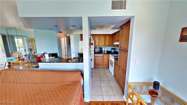 8161 Moyer Ln, Bokeelia, FL 33922 - kitchen with white range with electric cooktop, light tile patterned flooring, brown cabinets, under cabinet range hood, and a peninsula