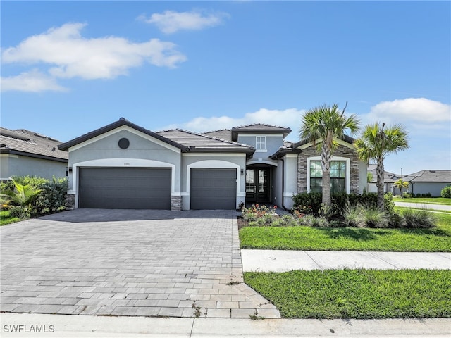view of front of home with stone siding, decorative driveway, stucco siding, an attached garage, and french doors