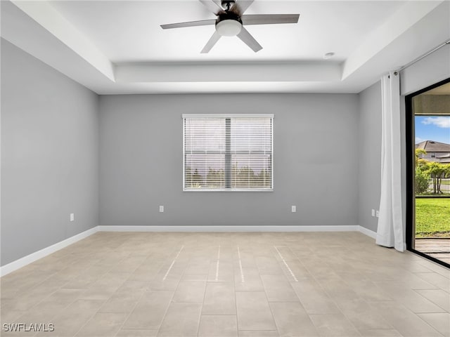 spare room featuring a raised ceiling, plenty of natural light, and ceiling fan