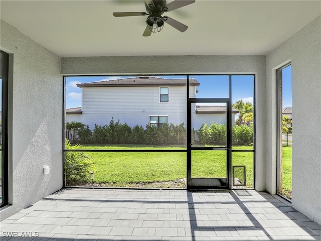 unfurnished sunroom featuring a ceiling fan