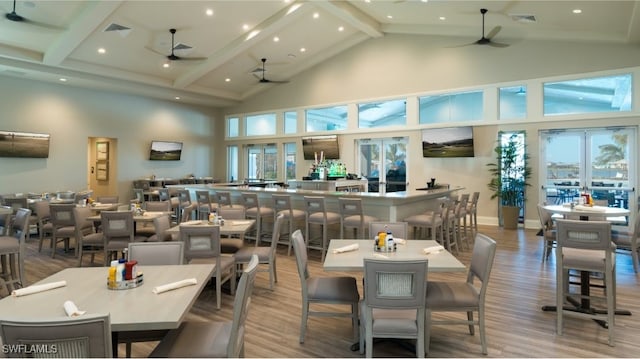 dining space featuring ceiling fan, high vaulted ceiling, beamed ceiling, wood finished floors, and recessed lighting