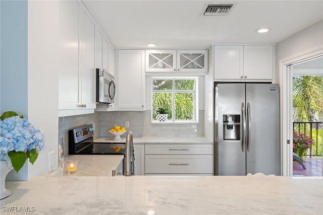 kitchen with appliances with stainless steel finishes, white cabinetry, decorative backsplash, light stone countertops, and recessed lighting