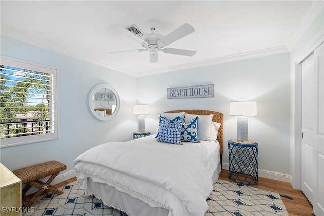 bedroom with a closet, light wood-type flooring, crown molding, baseboards, and a ceiling fan