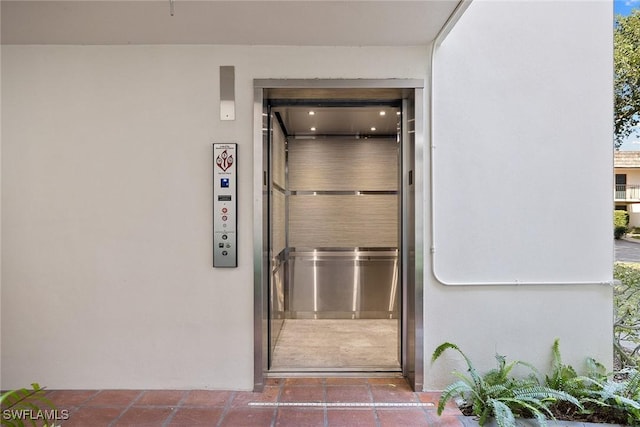 view of exterior entry featuring stucco siding and elevator