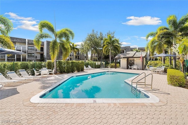 community pool with a patio area and fence