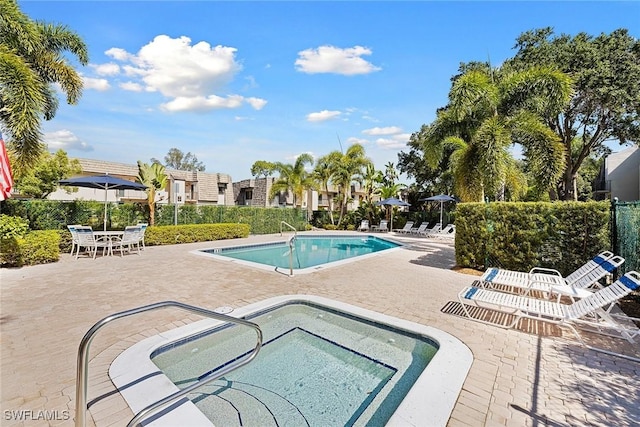 community pool with a hot tub and a patio area