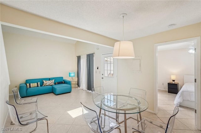 dining space featuring light tile patterned floors, a textured ceiling, and baseboards