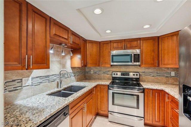 kitchen with stainless steel appliances, a sink, decorative backsplash, light stone counters, and recessed lighting