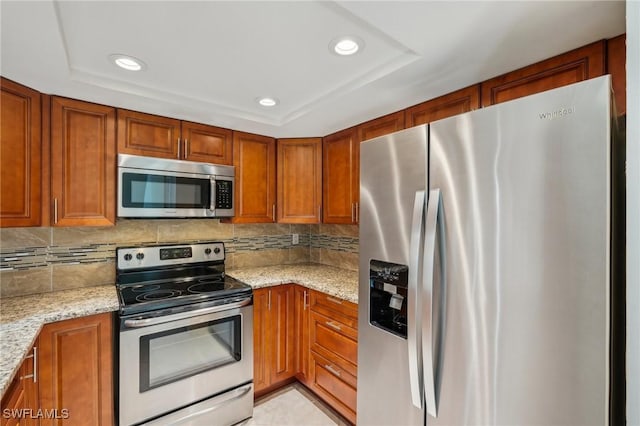 kitchen featuring appliances with stainless steel finishes, brown cabinetry, backsplash, and recessed lighting