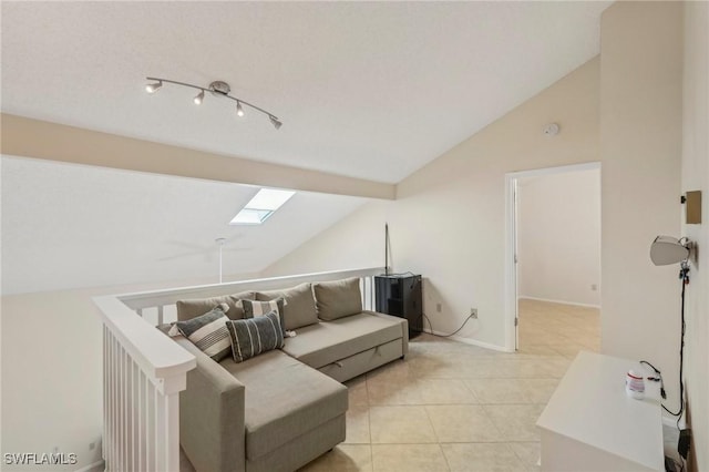living area with vaulted ceiling, light tile patterned floors, a skylight, and baseboards