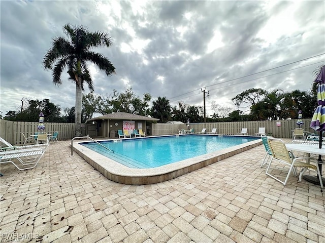 community pool with fence and a patio area