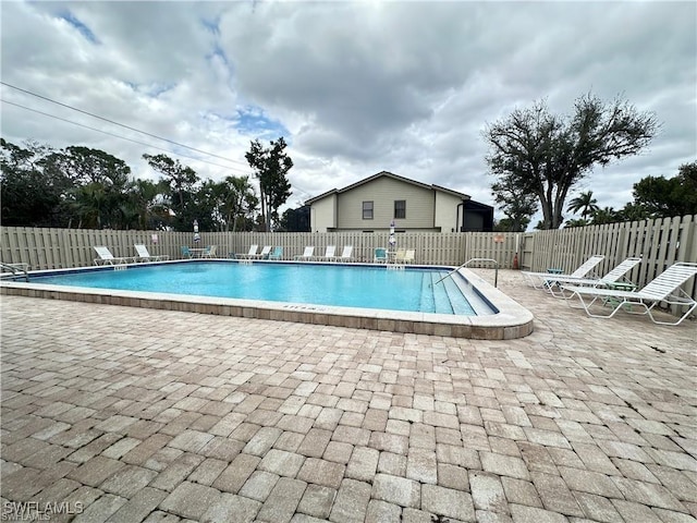 community pool with fence and a patio area