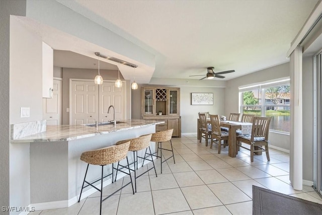 26740 Rosewood Pointe Ln Unit 102, Bonita Springs, FL 34135 - kitchen with a sink, a breakfast bar, ceiling fan, a peninsula, and baseboards