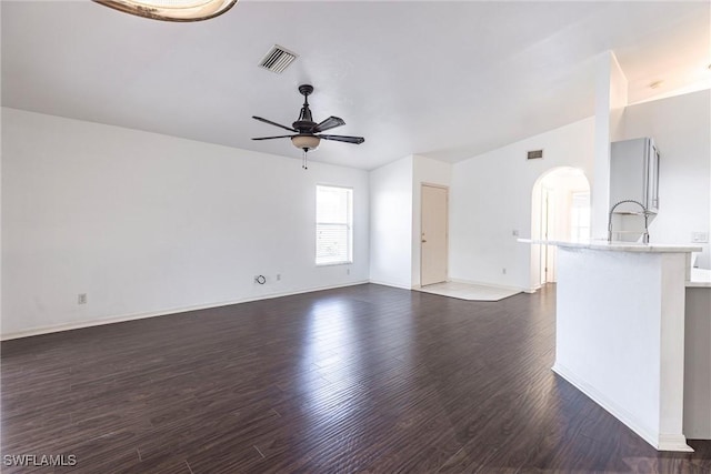 497 Bethany Village Cir, Lehigh Acres, FL 33936 - unfurnished living room featuring a ceiling fan, arched walkways, dark wood-style floors, baseboards, and a sink