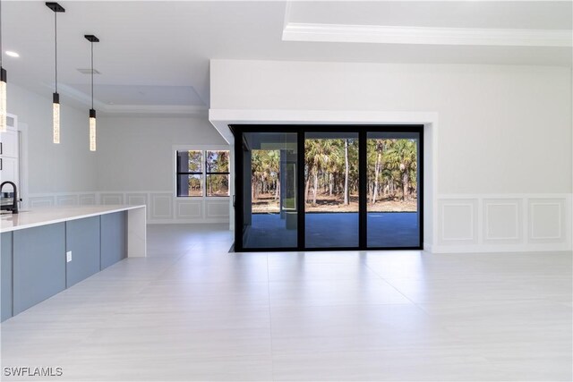 2583 18th Ave SE, Naples, FL 34117 - unfurnished living room featuring ornamental molding, a decorative wall, a raised ceiling, wainscoting, and a sink