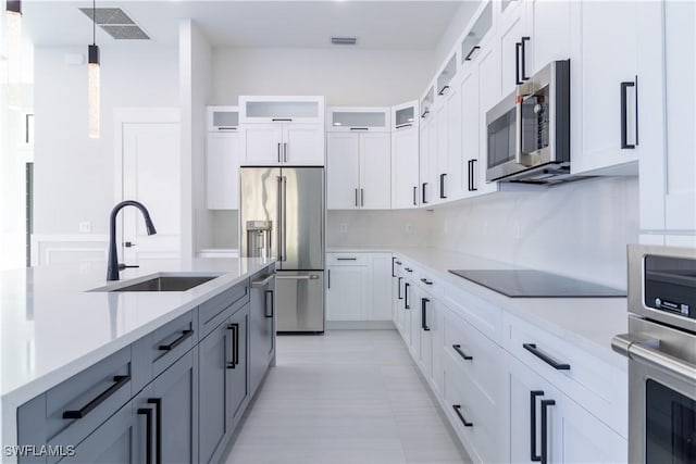2583 18th Ave SE, Naples, FL 34117 - kitchen featuring a sink, appliances with stainless steel finishes, glass insert cabinets, hanging light fixtures, and white cabinets