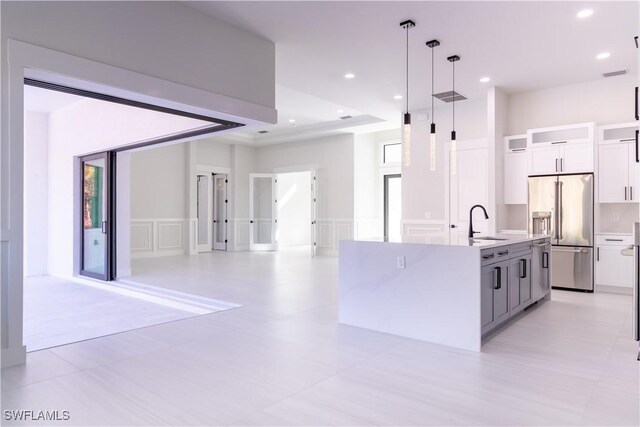2583 18th Ave SE, Naples, FL 34117 - kitchen with high end fridge, white cabinetry, open floor plan, light countertops, and a kitchen island with sink