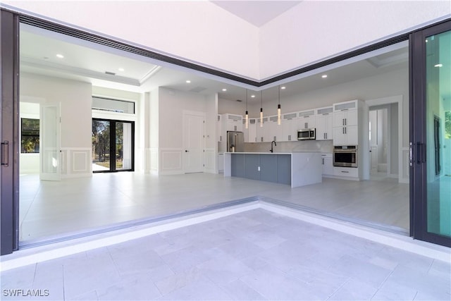 2583 18th Ave SE, Naples, FL 34117 - unfurnished living room featuring french doors, a decorative wall, a sink, a towering ceiling, and recessed lighting