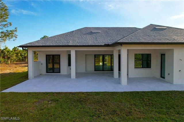2583 18th Ave SE, Naples, FL 34117 - back of property featuring a lawn, stucco siding, roof with shingles, and a patio area