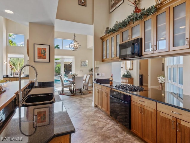 622 Bimini Ave, Marco Island, FL 34145 - kitchen featuring black appliances, a high ceiling, dark countertops, healthy amount of natural light, and glass insert cabinets