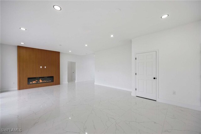 3300 18th St W, Lehigh Acres, FL 33971 - unfurnished room featuring recessed lighting, light marble finish floors, a glass covered fireplace, and baseboards