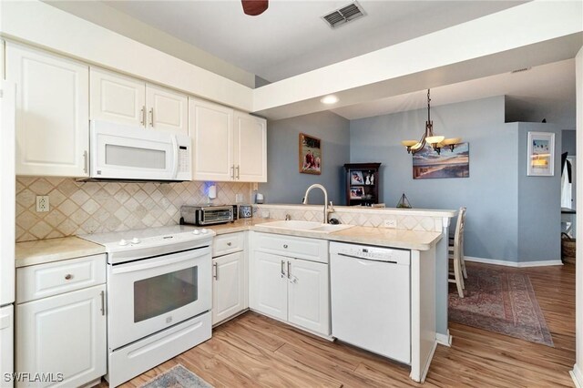9750 Sassafras Ct, Estero, FL 33928 - kitchen featuring white appliances, a sink, a peninsula, backsplash, and light wood-style floors