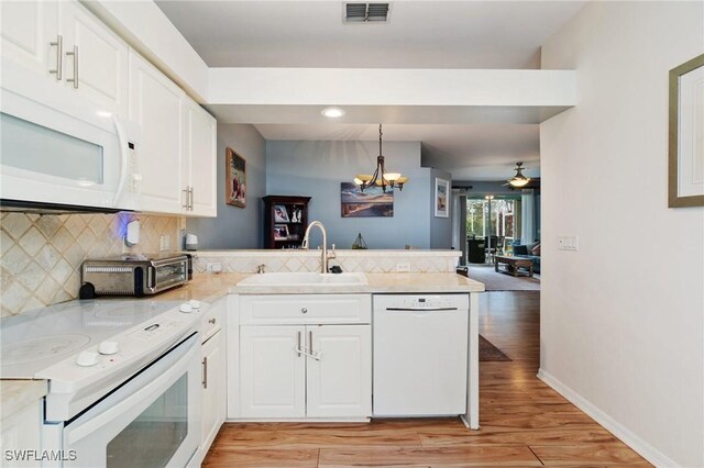 9750 Sassafras Ct, Estero, FL 33928 - kitchen featuring white appliances, a sink, a peninsula, light wood-type flooring, and a chandelier